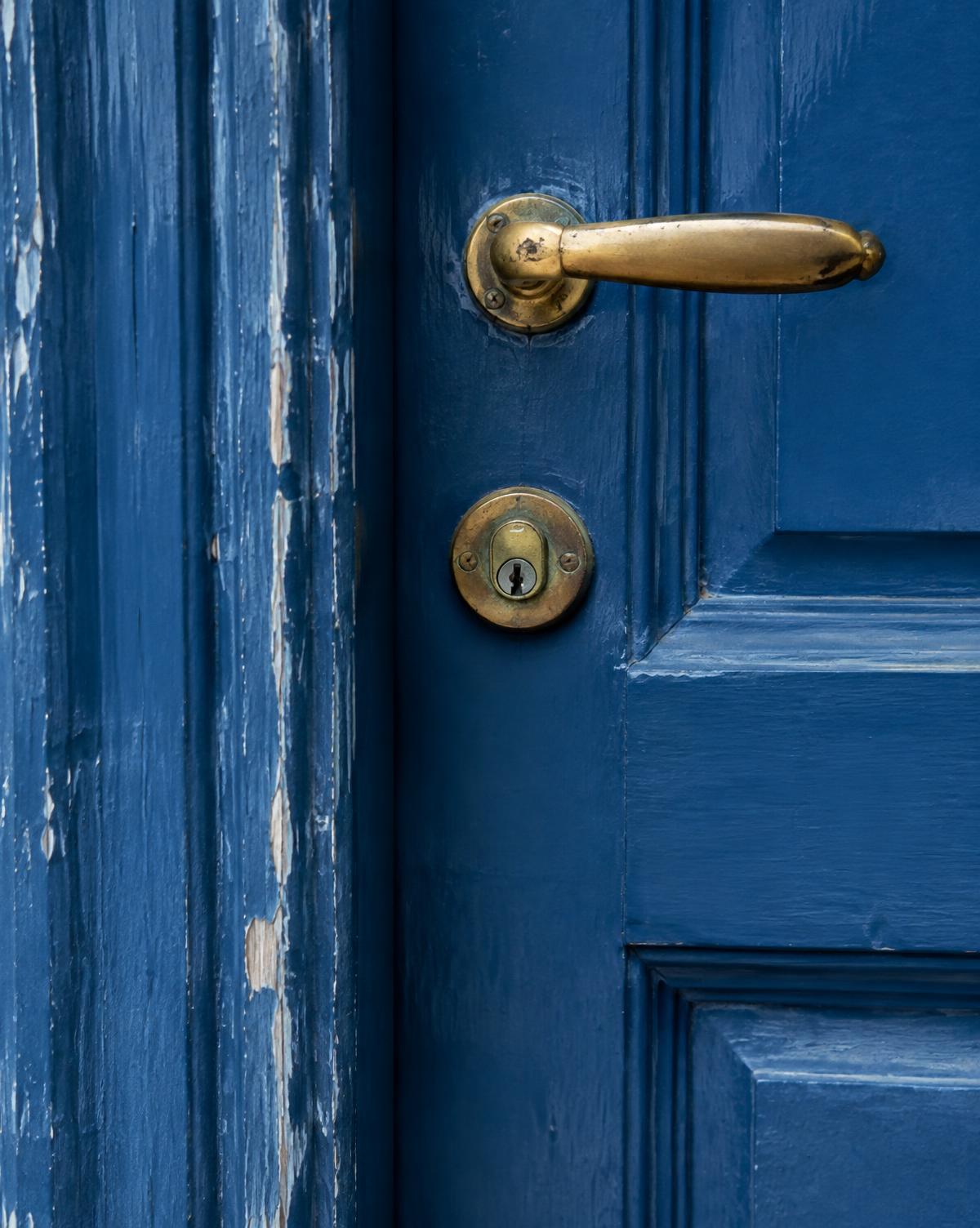 A weathered deep blue front door with old brass hardware
